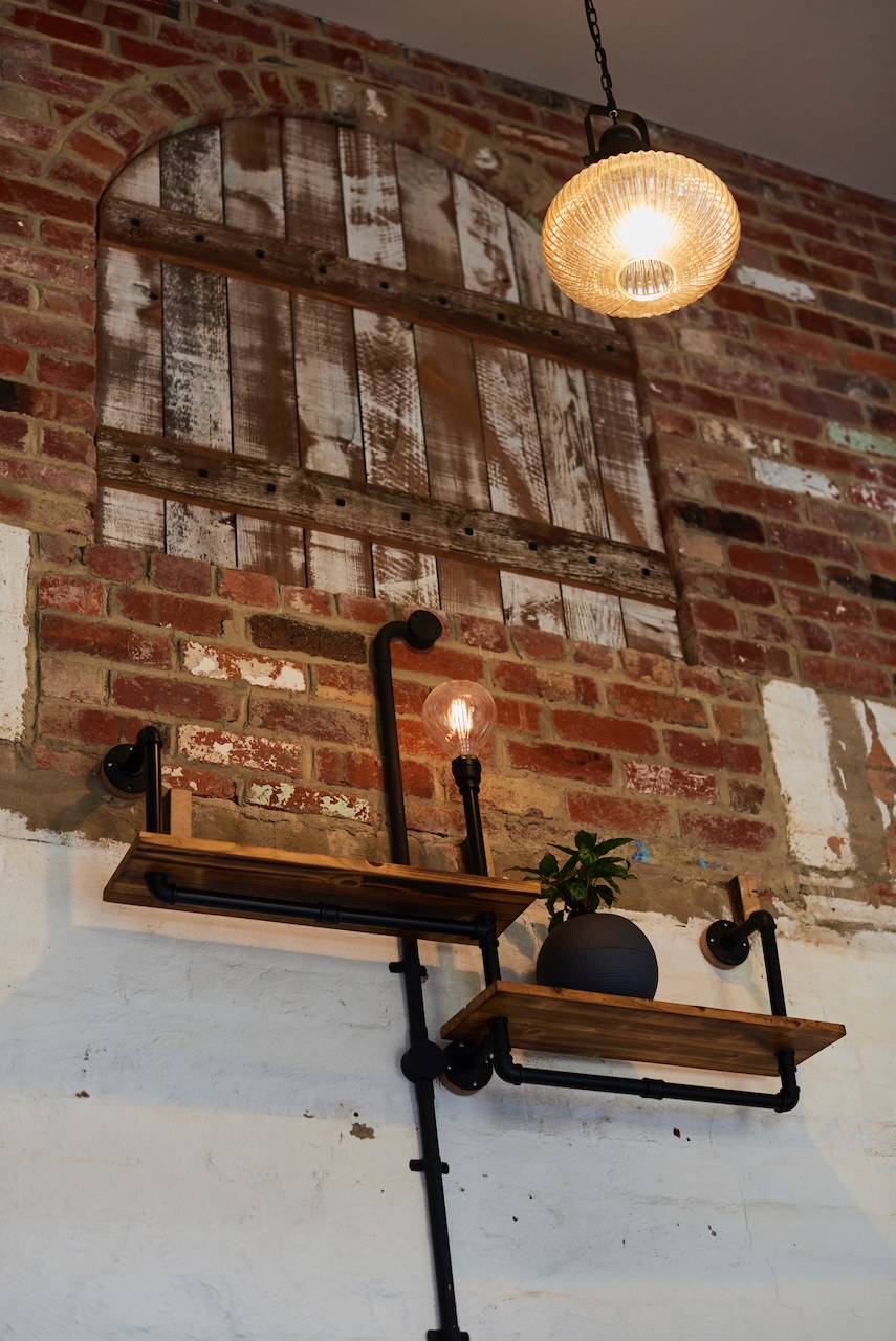 Lanes End pipe shelf and Edison light beneath a brick arch